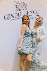 Two women at Gindulgence festival holding drinks.