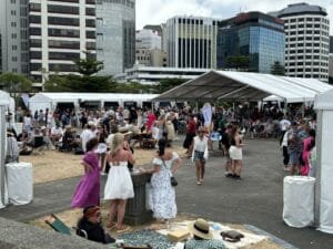 Outdoor event with large crowd and white tents