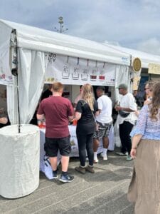 People gather at food stall in outdoor market.
