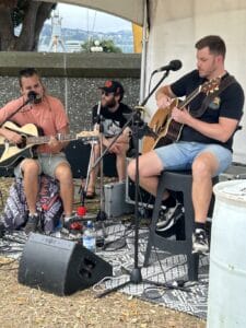 Three musicians performing outdoors with guitars