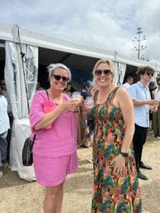 Two women smiling and holding drinks at a festival