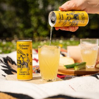 Alchemy & Tonic being poured from a can into a glass in a picnic setting