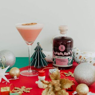 Pavlova Bliss Cocktail with Dabblers Gin bottle and Christmas decorations on a red table cloth