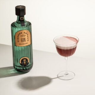 Strange Nature Clover Club Cocktail next to a bottle of Strange Nature Gin